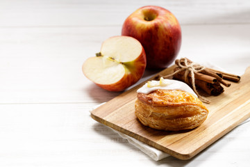 Naklejka na ściany i meble piece of cinnamon apple pie on a wooden board with fresh apple in background, autumn food concept