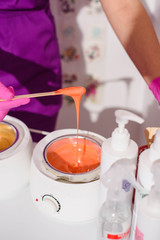 depilation and beauty concept - procedure of hair removing on leg beautiful woman with sugar paste or wax honey and black gloves hand