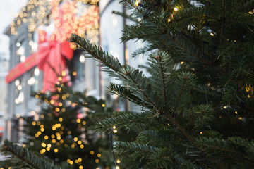 Christmas tree with garland and blurred luxury shopping mall in background. Outdoor. Xmas. Winter.