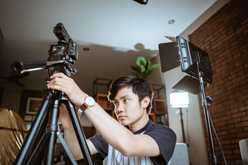 asian young man vlogger preparing camera to create their vlog content at home