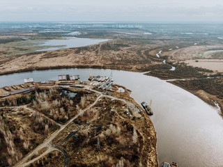 Transportation and loading of river ships. Spring, wide river, fields and forest. Panorama from the air.