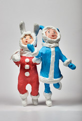 Christmas toys made of paper and cotton wool. Running joyful boy and girl in hare costumes. Close-up on white background.