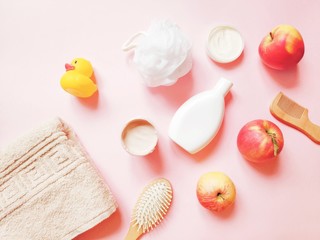 Beige towel, shampoo bottle, white kaolin clay, face cream, apples, wooden hair brushes. Cosmetics with vitamin c for skin and hair care