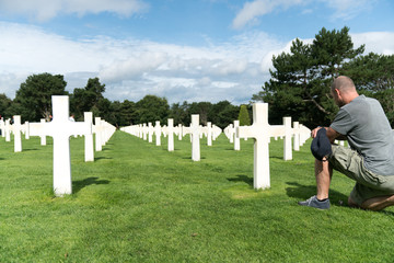 middle-aged man remembering his fallen grandfather at the American Cemetery in Omaha Beach