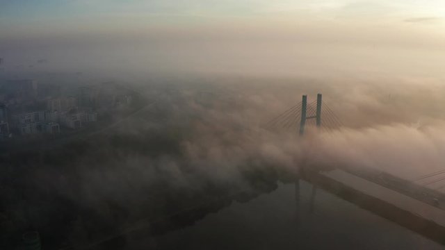 Aerial view of a bridge surrounded by fog at sunrise. Flight under the bridge. Aerial view of the Siekierkowski, Bridge in beautiful fog. Warsaw, Poland. 