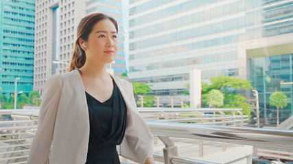 Beautiful Business Woman Going To Work With Wireless Earphones Walking Near Office Building in City. Portrait Of Successful Business