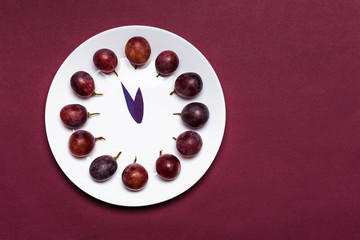 Clock of 12 piece grapes on red background. New Year concept. Spanish tradition for the new year.