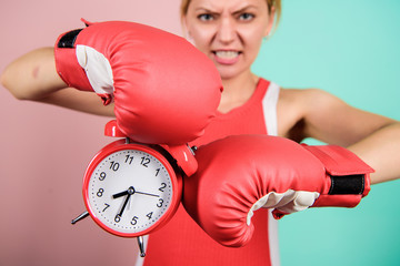 Battle for self discipline. Woman holding clock boxing gloves. Boxer fighting with alarm clock....