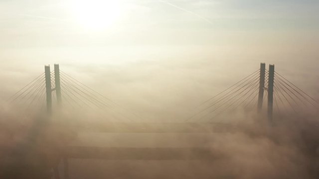 Aerial view of fog at sunrise over the bridge Siekierkowski, Warsaw. Drone flies above the clouds of fog and the Vistula river at sunrise. Drone Shot 4K. 