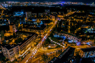 Fototapeta na wymiar A fabulous New Year's city in blue and yellow neon lights with streets, cars and lights illuminated at night. Beautiful magical city aerial view. Aerial photography.