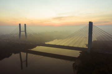 Aerial view of the Siekierkowski Bridge in beautiful fog. Warsaw, Poland. Drone shot at the traffic of vehicle traveling in traffic jam on a bridge over a river.