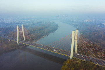 Aerial view of the landmark of the bridge in the fog in Warsaw. Drone flies above the clouds of fog and the Vistula river at sunrise. Spectacular Sunrise with low fog. bridge Siekierkowski, Warsaw.