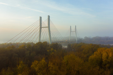 Aerial view of a bridge with cars in the fog. Warsaw. Poland. Drone shot at the traffic of a vehicle traveling in traffic jam on a bridge over a river. Drone shot into the fog at sunrise over a bridg