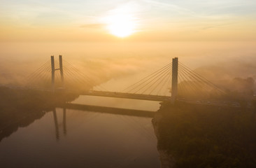 Drone shot into the fog at sunrise over a bridge at sunrise. Cars driving into the Fog along the Siekierkowski, Bridge at sunrise. Warsaw. Poland.