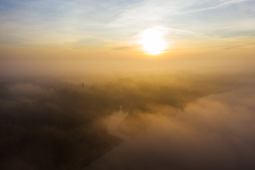 Drone shot above the clouds towards the sun. The sky above the clouds on a sunny morning. Aerial view of low fog over a river at sunrise. 4K Drone shot.