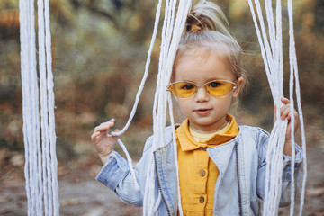 little pretty girl posing for a photo while walking with her parents in autumn park, an infinitely...