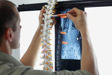 Professional with  model  of spine watching image of chest  at x-ray film viewer....