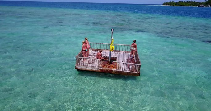 Young women exploring seabed with coral and colorful fish from a floating platform over turquoise water in Barbados