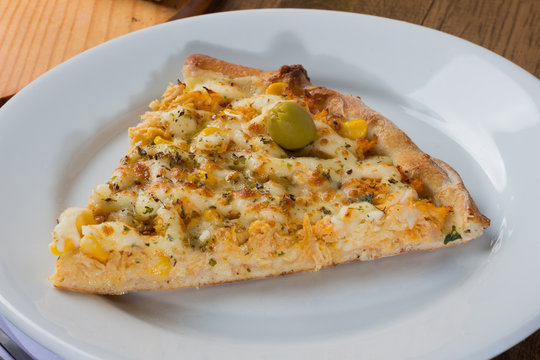Delicious Pizza Chicken Catupiry flavor served on a wooden board. Made with Mozzarella, Chicken, Creamy Curd, Green Olives, Corn and Red Tomato Sauce. Pizza slice served on the plate 5.