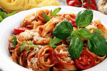 tagliatelle pasta with tomato sauce parmesan basil on rustic background