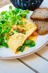 Tasty homemade omelette with fresh salmon served with lettuce on top in white ceramic vintage plate