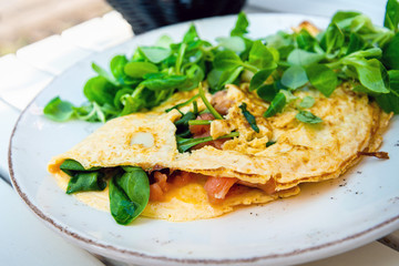 Tasty homemade omelette with fresh salmon served with lettuce on top in white ceramic vintage plate