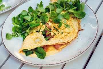 Tasty homemade omelette with fresh salmon served with lettuce on top in white ceramic vintage plate