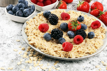 Bowl of oatmeal porridge with banana, raspberries coconut and caramel sauce on rustic table, hot and healthy food for Breakfast