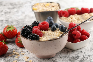 Bowl of oatmeal porridge with banana, raspberries coconut and caramel sauce on rustic table, hot and healthy food for Breakfast