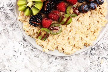 Bowl of oatmeal porridge with banana, raspberries coconut and caramel sauce on rustic table, hot and healthy food for Breakfast