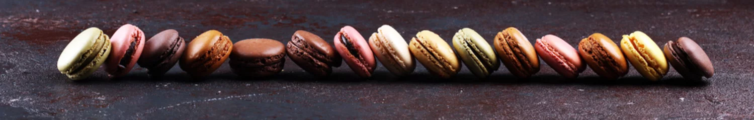 Poster Süße und bunte französische Makronen oder Macaron auf dunkelschwarzem Hintergrund, Dessert. © beats_