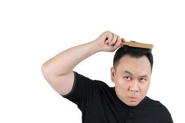 Asian bald man alopecia hand holding comb on bald head isolated on white background. Human hair loss solution and hair transplant concept.