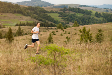 Running fitness man sprinting outdoors with beautiful mountains landscape on background. Caucasian sport male runner training for marathon.