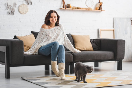 Beautiful Happy Woman Sitting On Sofa With Scottish Fold Cat On Floor