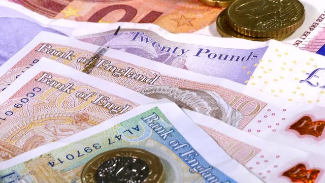 Close POV overhead dolly shot of notes and coins, by way of US dollars, euros and pounds sterling, with calculator buttons at the end of the shot.