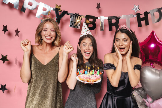 Image of caucasian party girls holding birthday cake with candles