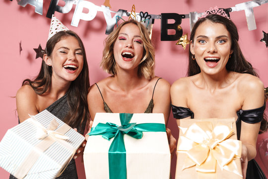 Image of caucasian party girls in fancy dresses holding birthday gift boxes