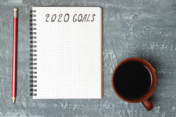 2020 goals, text on the paper in notepad, New Year promises concept, pencil, coffee cup, top view