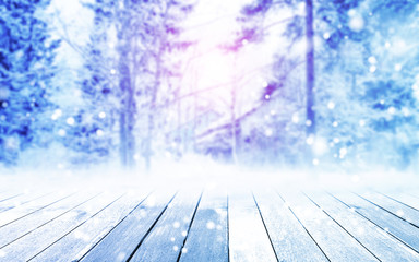 The table is wooden and there is free space for your text or product decoration. Landscape in the winter. Blurred branches of spruce and frost, bokeh.