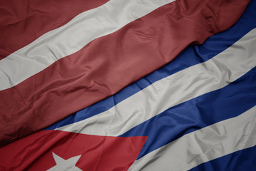 waving colorful flag of cuba and national flag of latvia.