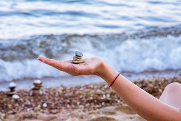 Fototapeta na wymiar Young woman hand with sea pebble turret