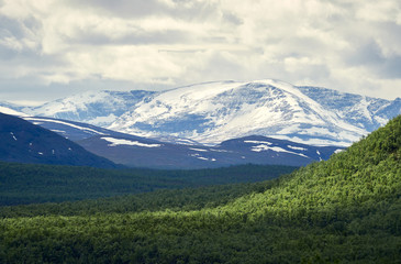 Fototapeta premium Mointains in Norway seen from Kilpisjarvi, Finland. Snowy peaks on a partly cloudu summer day.