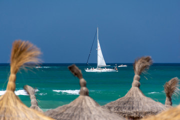 White yacht behind beach umbrellas on Mallorca island