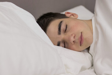 Obraz na płótnie Canvas portrait of young teenage man sleeping in bed