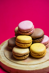 Colored macarons isolated on wooden dish, typical French dish