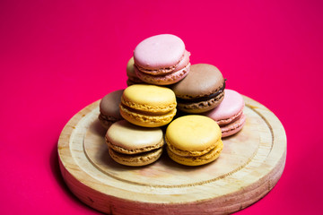 Colored macarons isolated on wooden dish, typical French dish