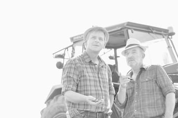 Black and white photo of Mature farmer holding soil while senior farmer discussing in field