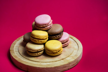 Colored macarons isolated on wooden dish, typical French dish