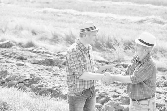 Black and white photo of farmers shaking hands in field