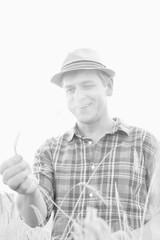 Black and white photo of mature farmer looking at wheat crop in field